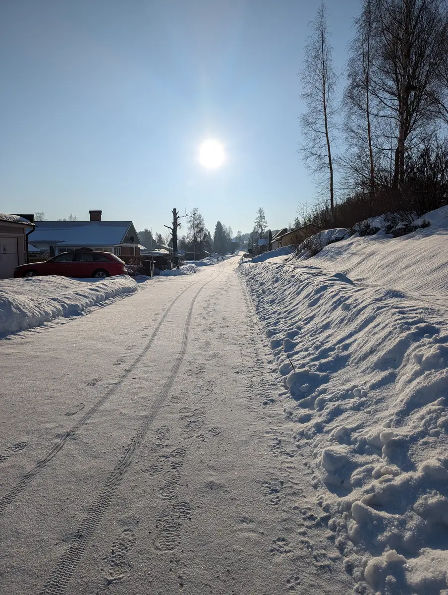 A snowy road with the sun shining