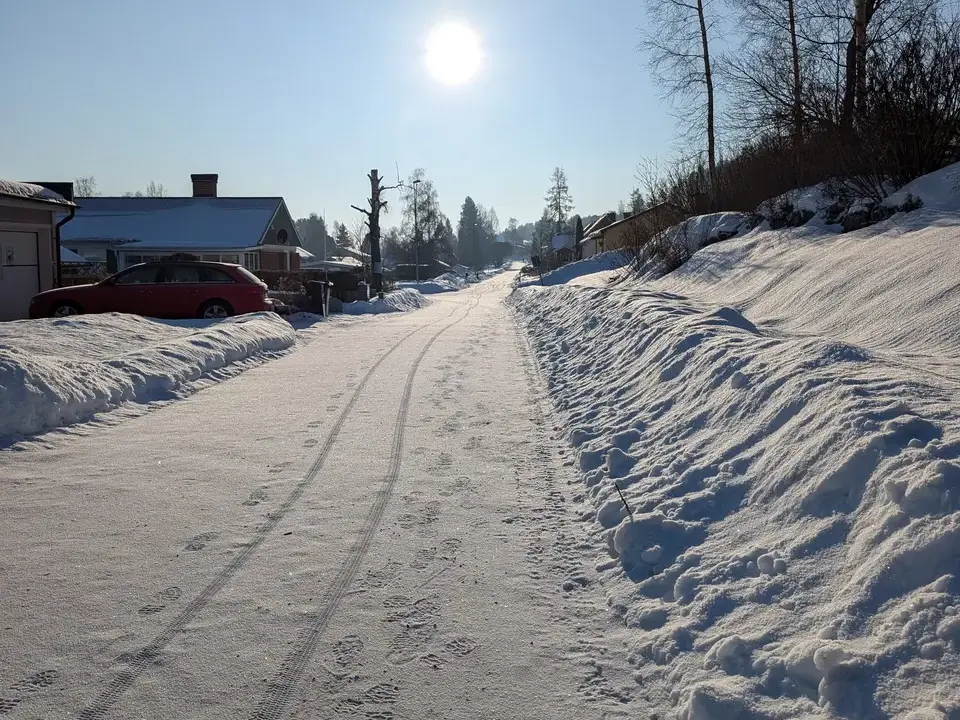 A snowy road with the sun shining